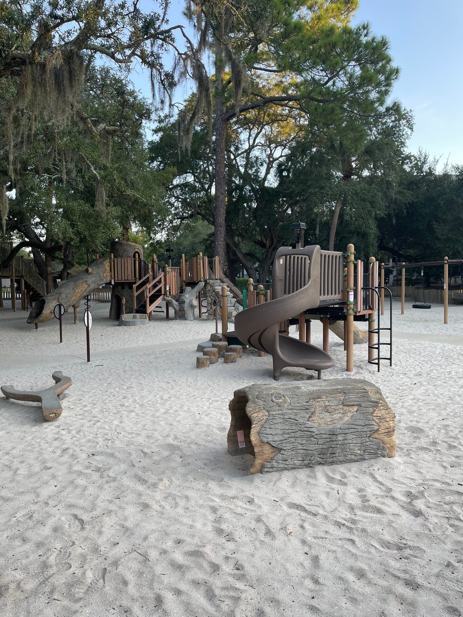 Slides and climbing equipment beneath the trees at Gregg Russell Harbour Town Playground