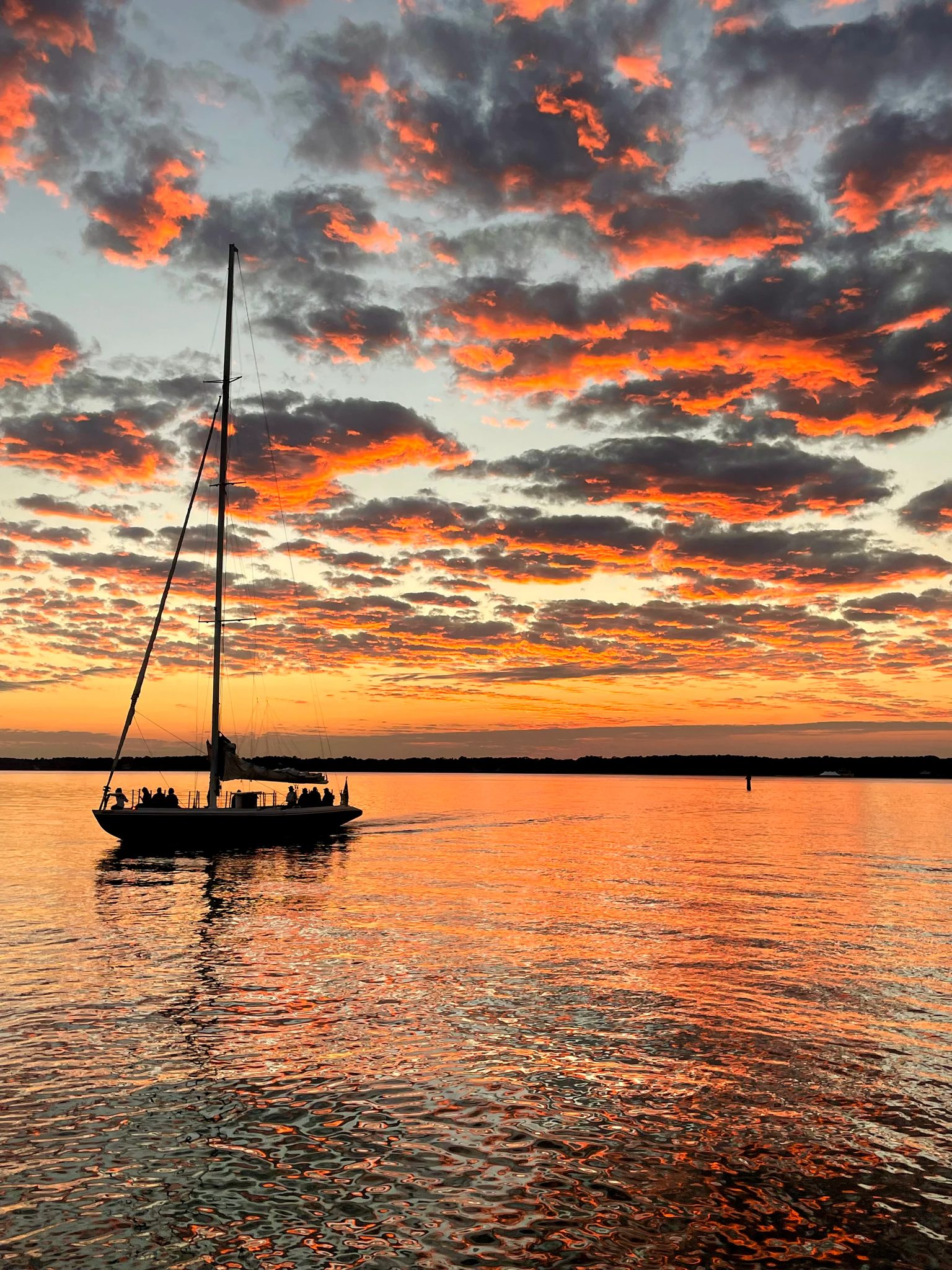 Sailboat silhouetted against an orange sunset at Harbour Town